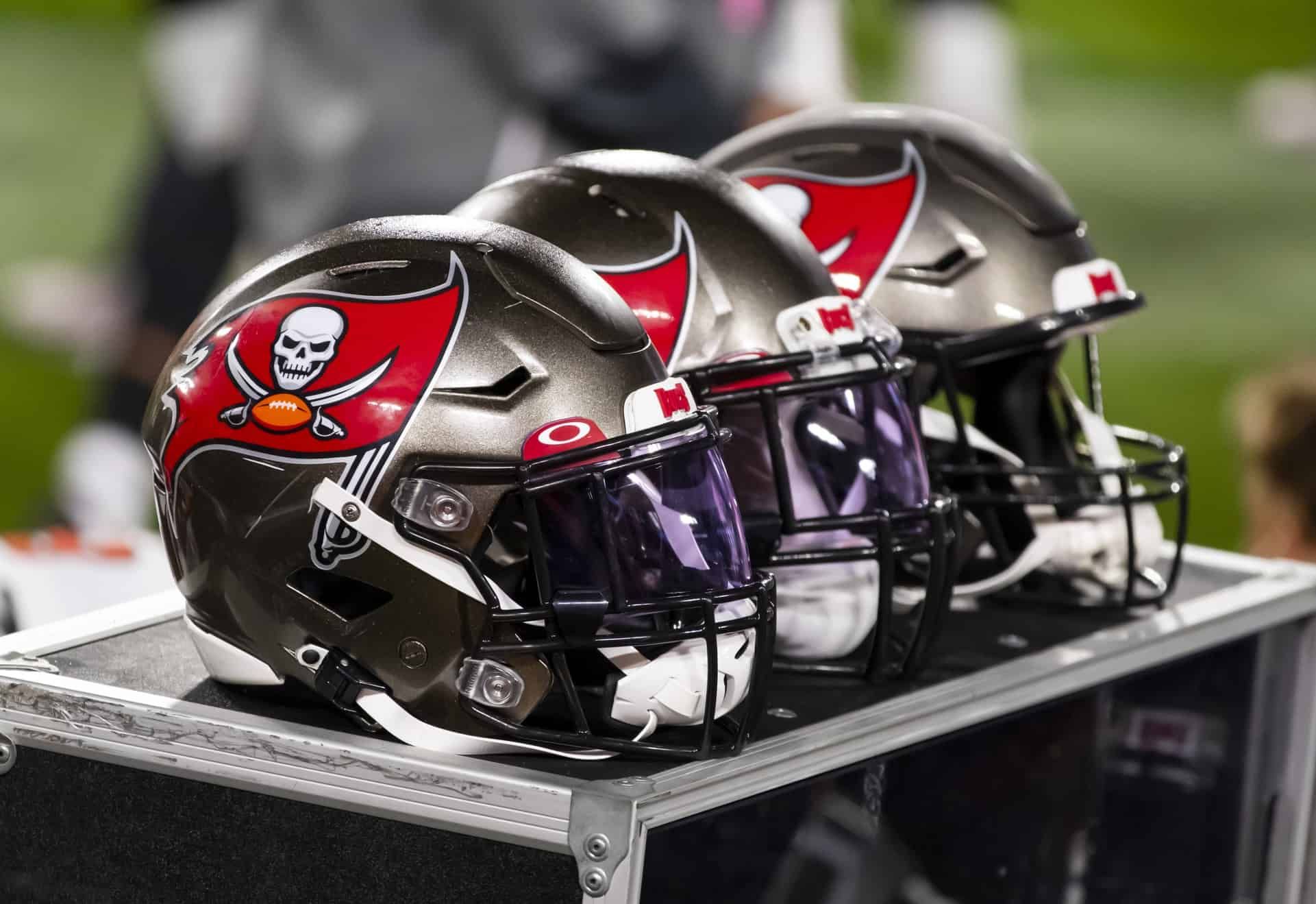 A trio of Tampa Bay Buccaneers helmets on top of a box on the Buccaneers' bench.