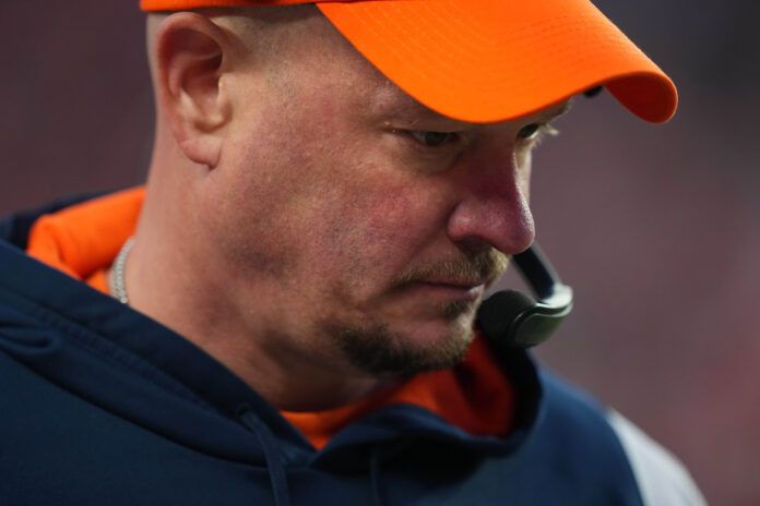 Former Denver Broncos head coach Nathaniel Hackett in an orange cap and navy hooded sweatshirt looking down at the ground