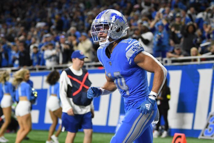 Amon-Ra St. Brown smiles as he runs back to the sideline after catching a touchdown pass from quarterback Jared Goff.