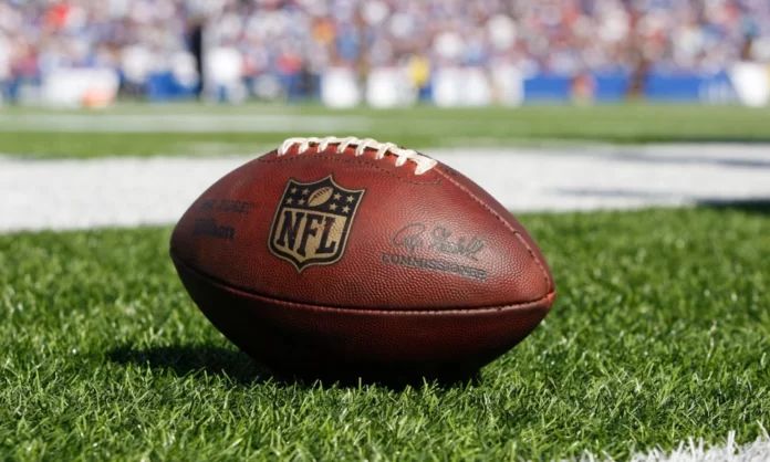 An official NFL football being shown on the sidelines of a game.