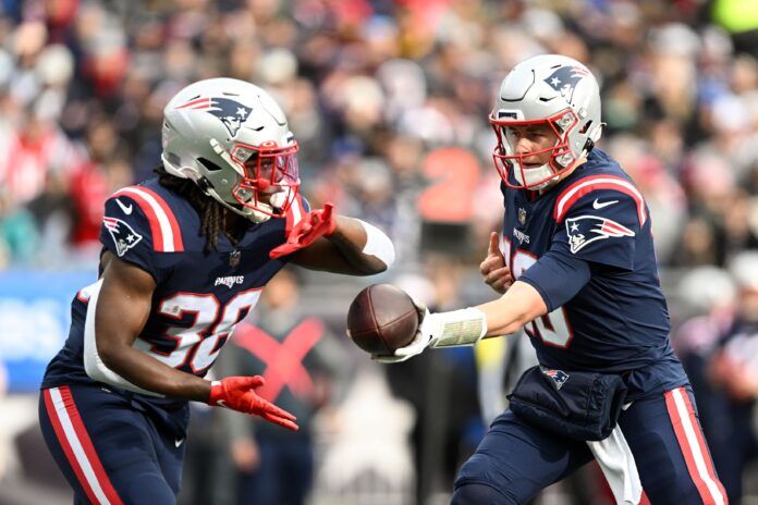 New England Patriots QB Mac Jones (10) hands the ball off to RB Rhamondre Stevenson (38).