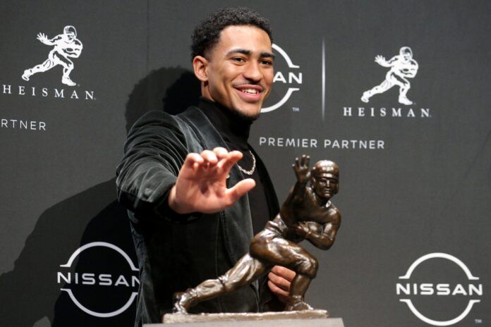 Bryce Young poses for pictures with the Heisman trophy during a press conference.