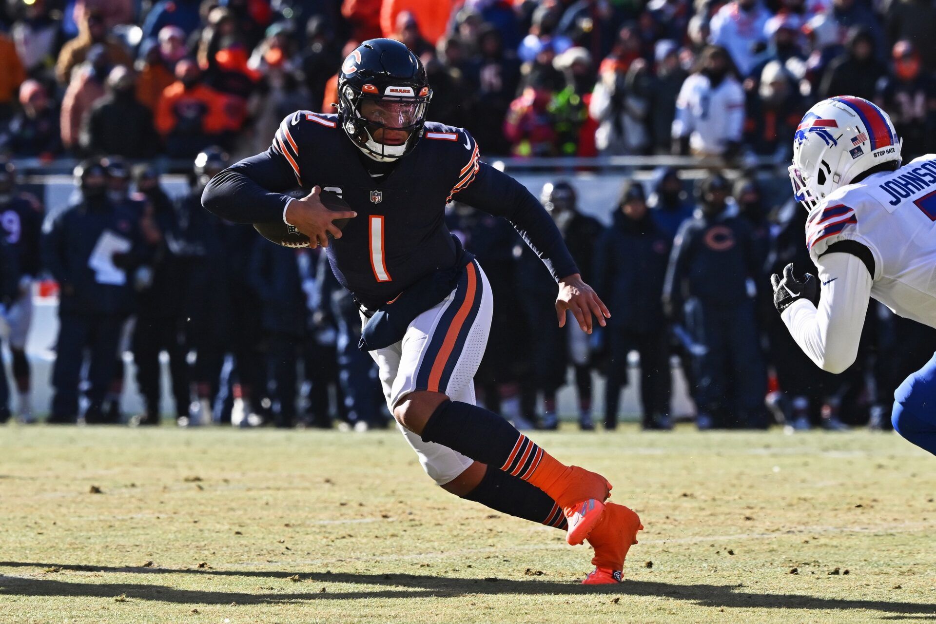 Chicago Bears QB Justin Fields (1) runs the ball away from a Buffalo Bills defender.