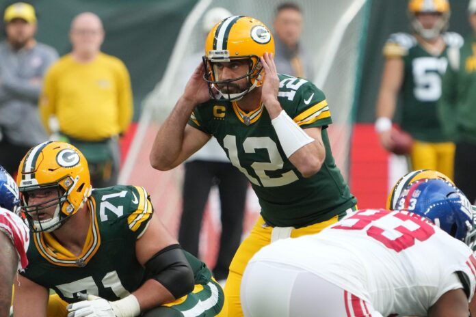 Green Bay Packers QB Aaron Rodgers (12) covers his ears before the snap.