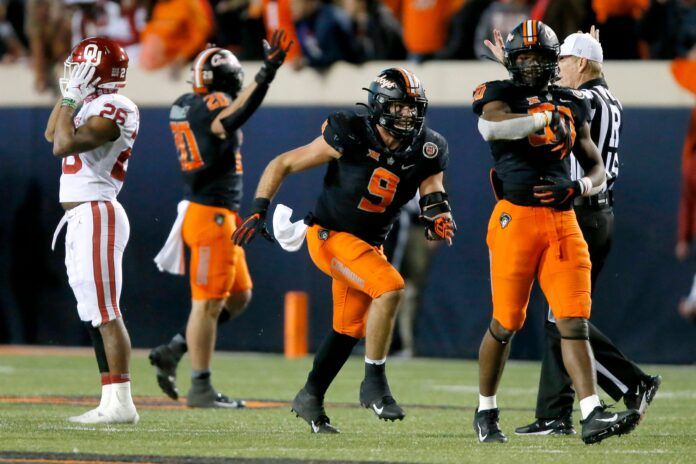 Brock Martin (9) and Collin Oliver (30) celebrate beside OU's Kennedy Brooks (26) after sacking Caleb Williams.