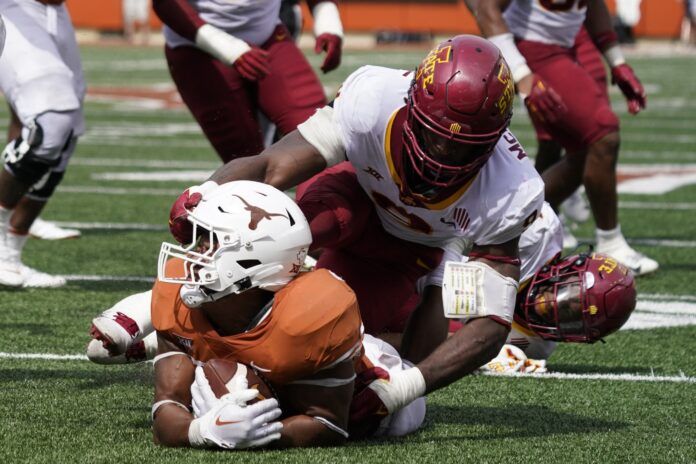 Texas Longhorns running back Roschon Johnson (2) is tackled by Iowa State Cyclones defender Will McDonald IV (9).