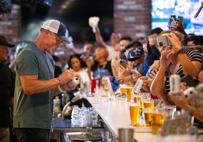 Troy Aikman smiles as he autographs fans’ memorabilia at Union Draft House.