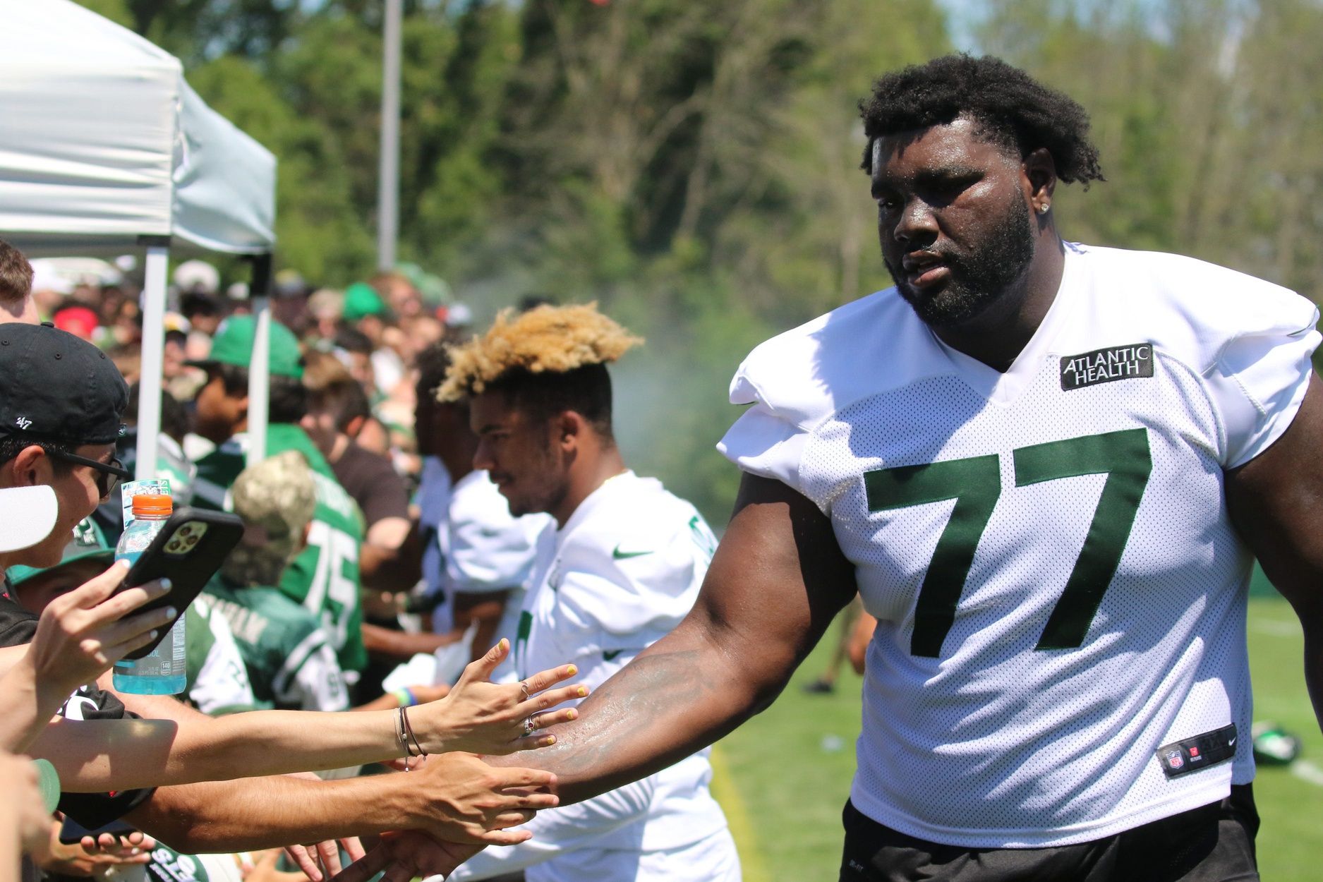 New York Jets OT Mekhi Becton signs autographs and takes photos with fans after practice.