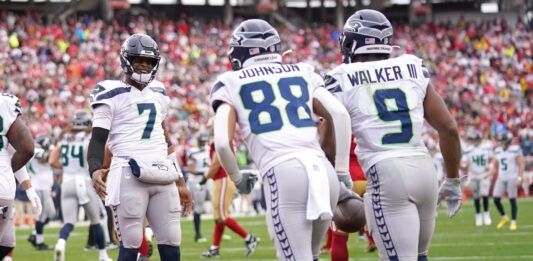Seattle Seahawks QB Geno Smith (7) celebrates with RB Kenneth Walker III (9) and Cade Johnson (88) after coring a touchdown.