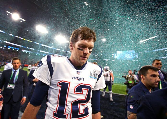 Confetti falls as New England Patriots quarterback Tom Brady (12) walks off the field after Super Bowl LII against the Philadelphia Eagles at U.S. Bank Stadium.