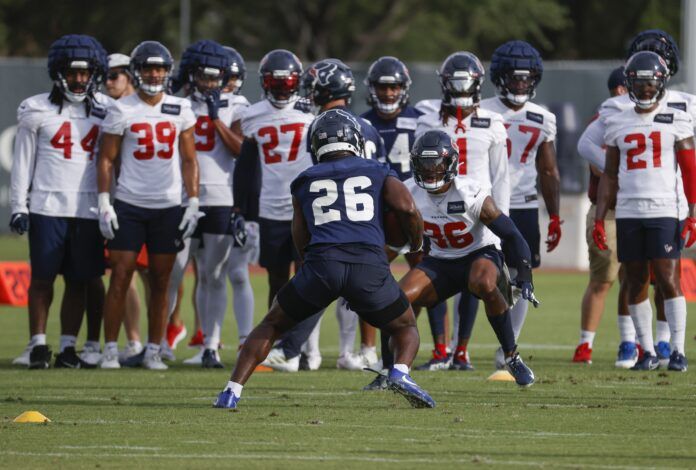 Houston Texans players performing a drill at minicamp while other players look on.