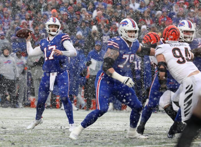 Bills quarterback Josh Allen looks for an open receiver while teammate Spencer Brown looks to block Bengals Sam Hubbard during the first half.