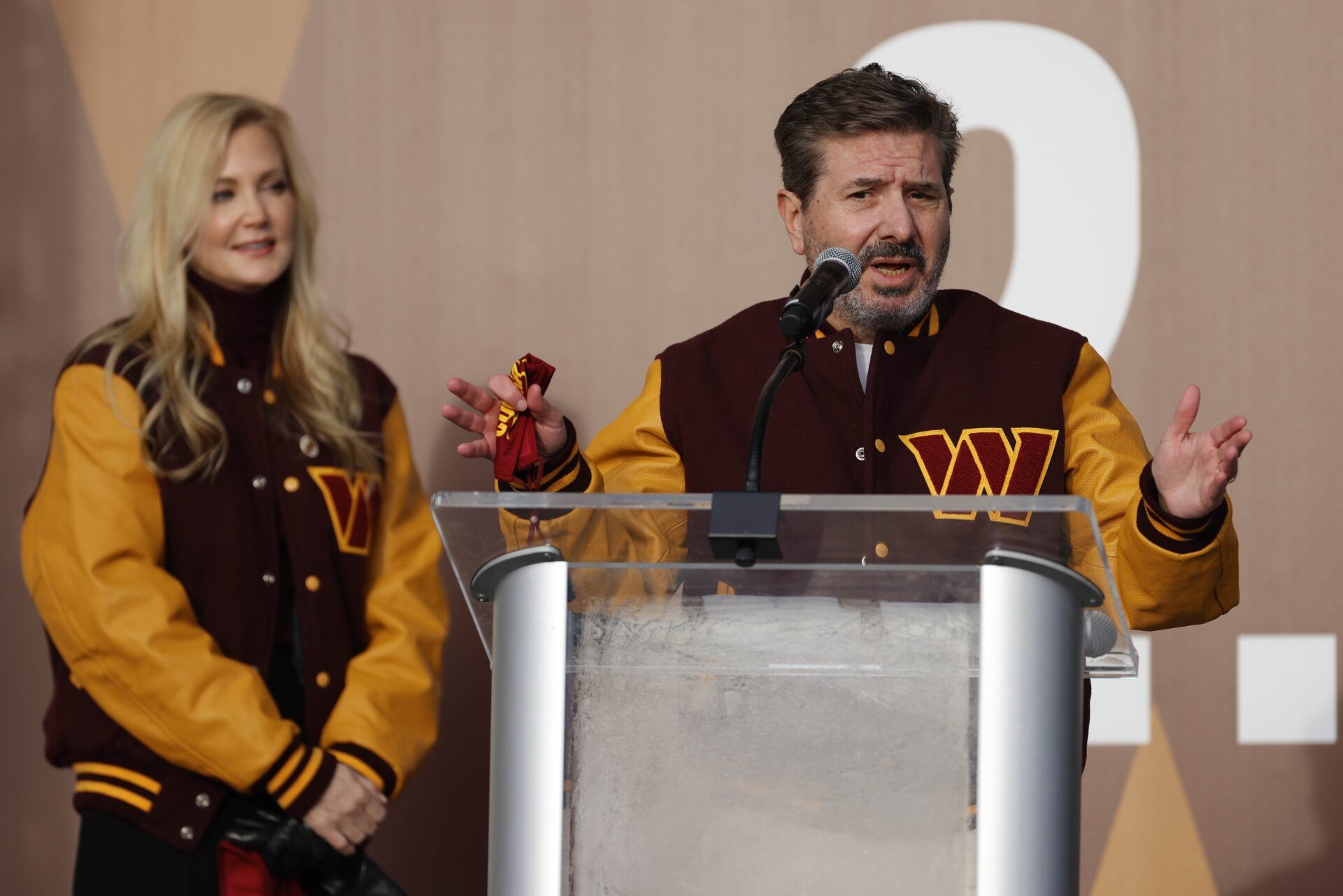 Dan Snyder speaks as co-owner Tanya Snyder (L) listens during a press conference revealing the Commanders as the new name for the formerly named Washington Football Team at FedEx Field.