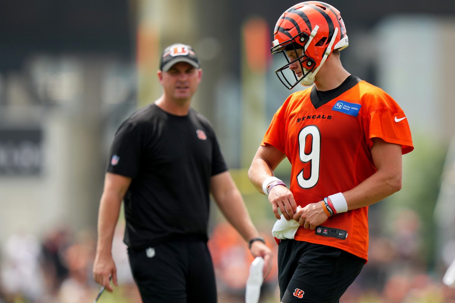 Joe Burrow (9) turns to talk to head coach Zac Taylor during training camp practice at the practice fields beside Paycor Stadium.