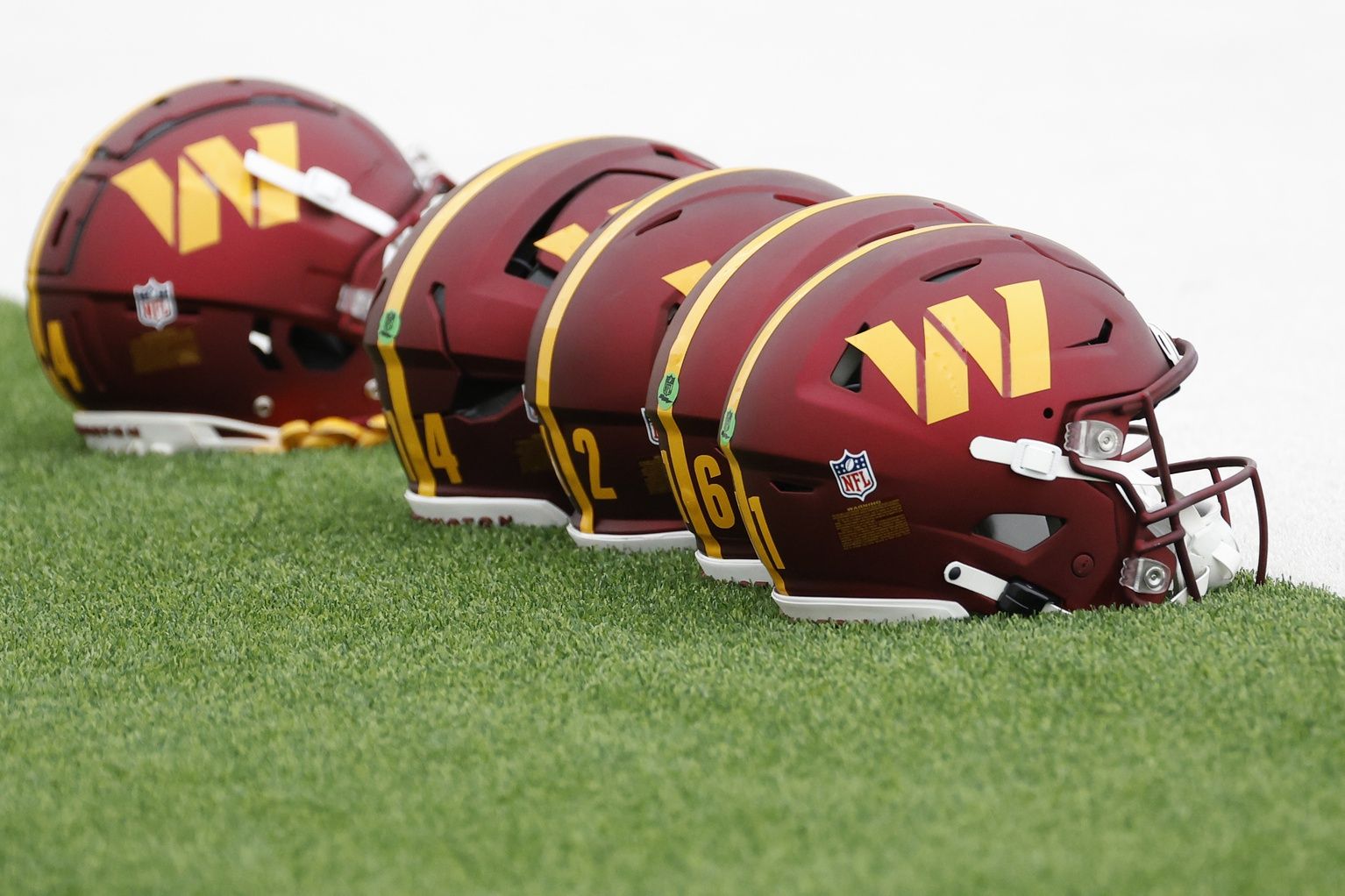 A row of Washington Commanders helmets displayed on the field.