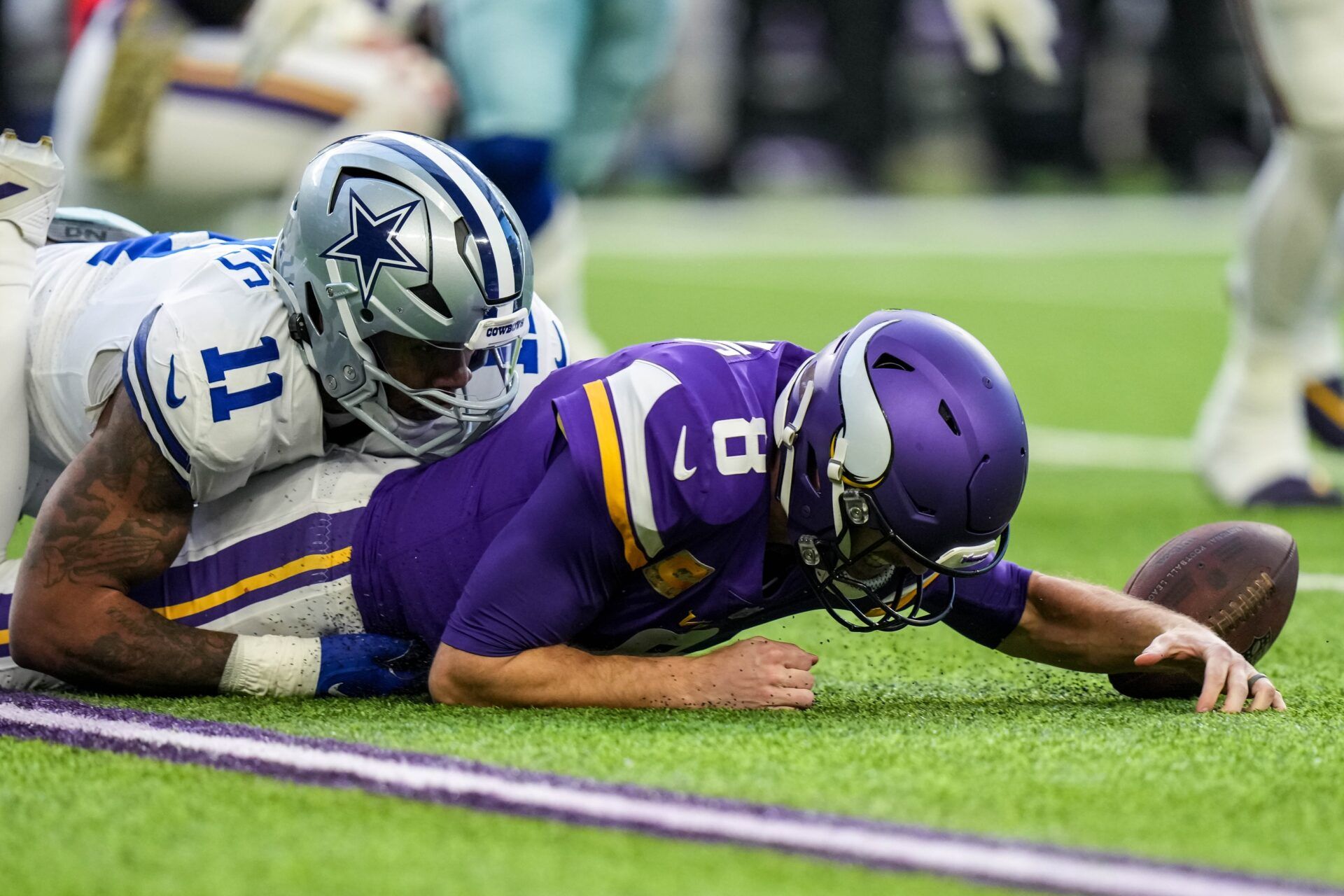 Micah Parsons (11) sacks Minnesota Vikings quarterback Kirk Cousins (8) and forces a fumble during the first quarter at U.S. Bank Stadium.