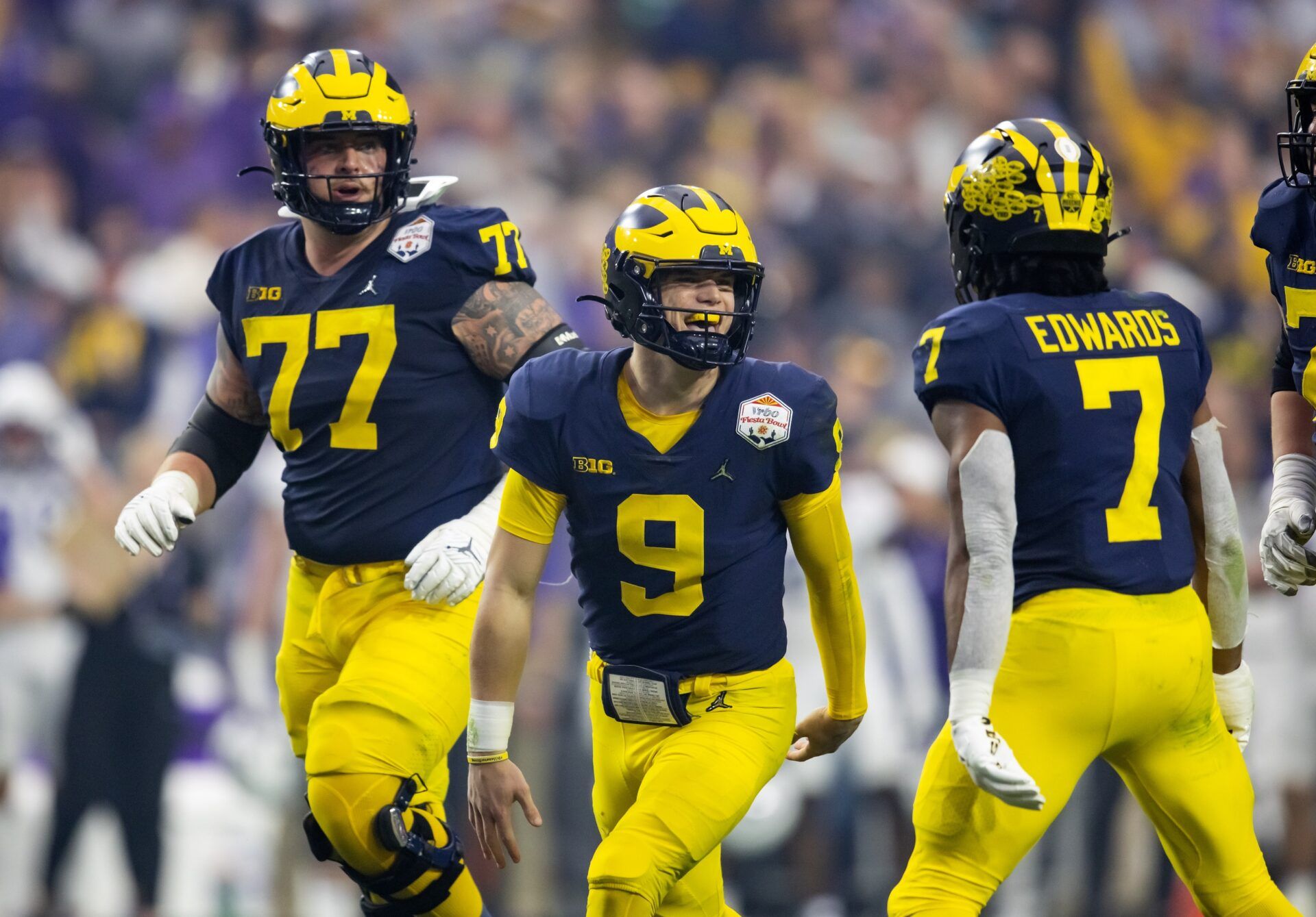 J.J. McCarthy (9) celebrates with running back Donovan Edwards (7) and offensive lineman Trevor Keegan (77) against the TCU Horned Frogs during the 2022 Fiesta Bowl at State Farm Stadium.