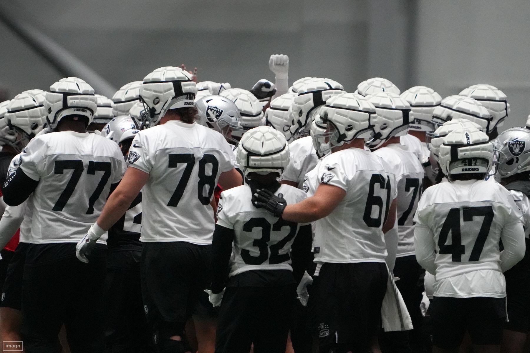 Las Vegas Raiders wearing Guardian helmet caps huddle during training camp at the Intermountain Health Performance Center.