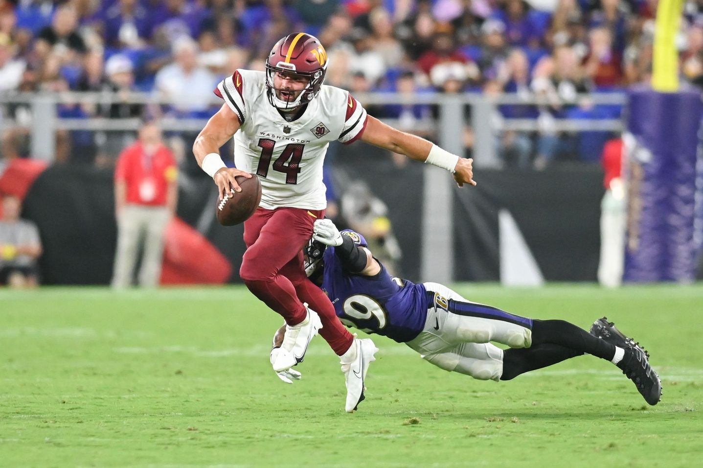 Washington Commanders QB Sam Howell (14) attempts to break free from a tackle against the Baltimore Ravens.