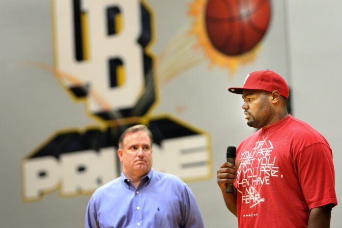 Former NFL offensive lineman Michael Oher and Sean Tuohy speak at a high school.