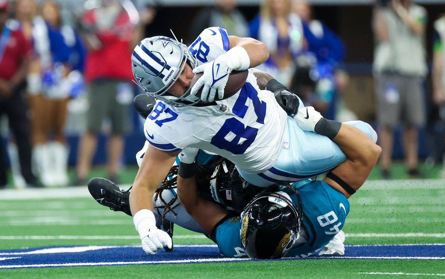 Jake Ferguson (87) tries for extra yardage as Jacksonville Jaguars linebacker Chad Muma (48) defends during the first quarter at AT&T Stadium.