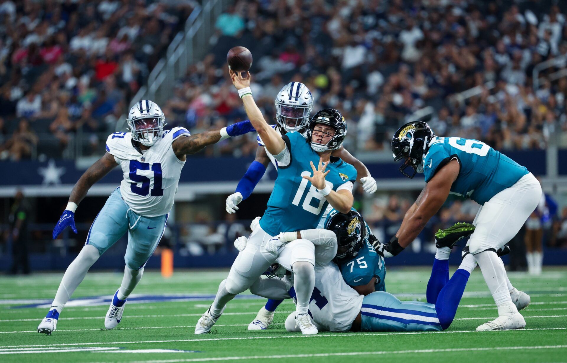 Nathan Rourke (18) runs away from Dallas Cowboys defenders and throws a touchdown pass during the second half at AT&T Stadium.