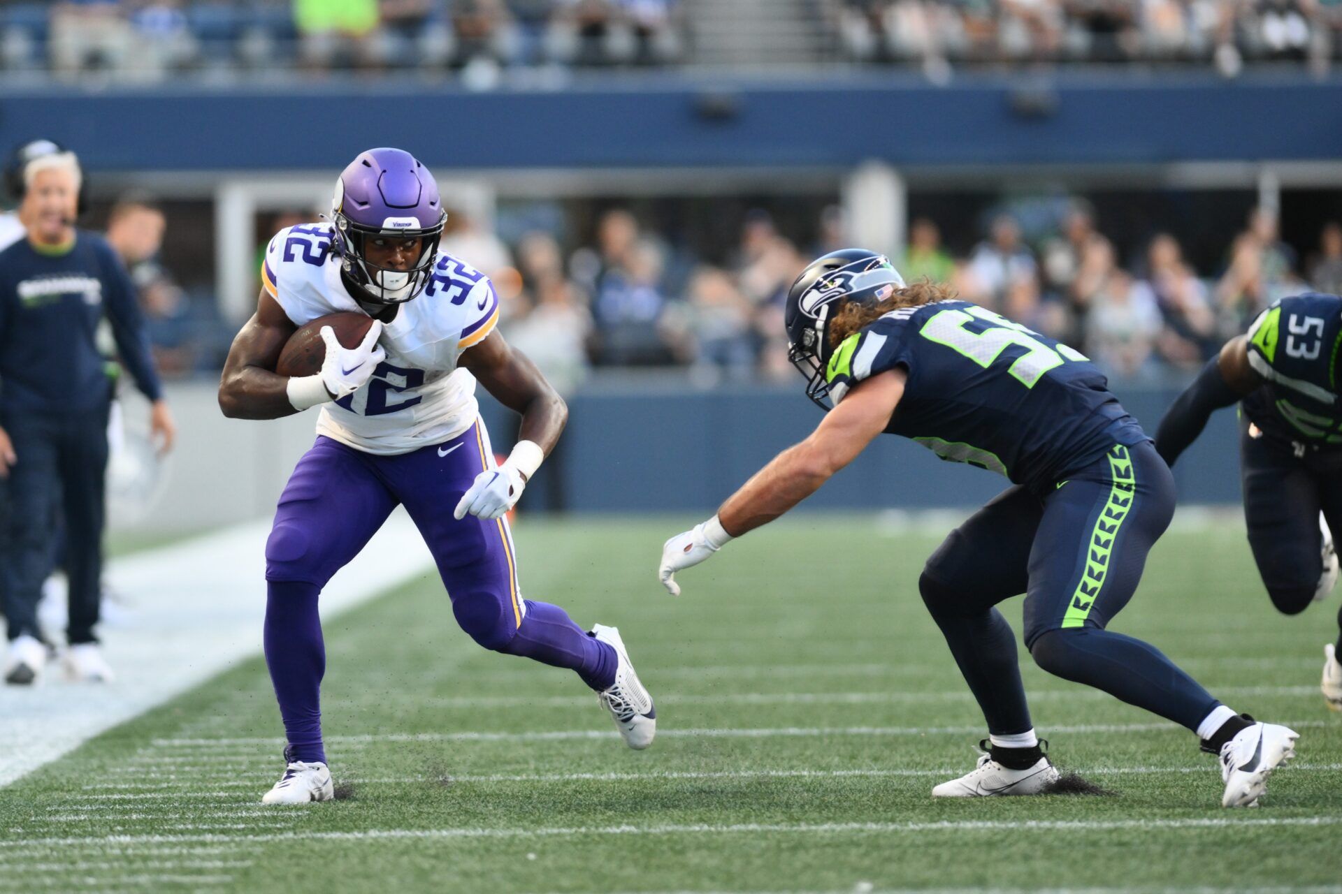 Ty Chandler (32) carries the ball while being defended by Seattle Seahawks linebacker Jon Rhattigan (59) after making a catch during the first half at Lumen Field.