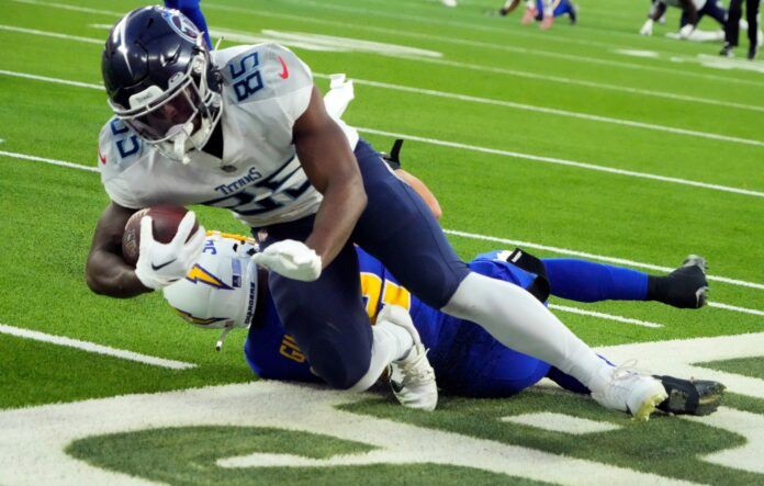 Tennessee Titans TE Chigoziem Okonkwo dives over a Los Angeles Chargers player.