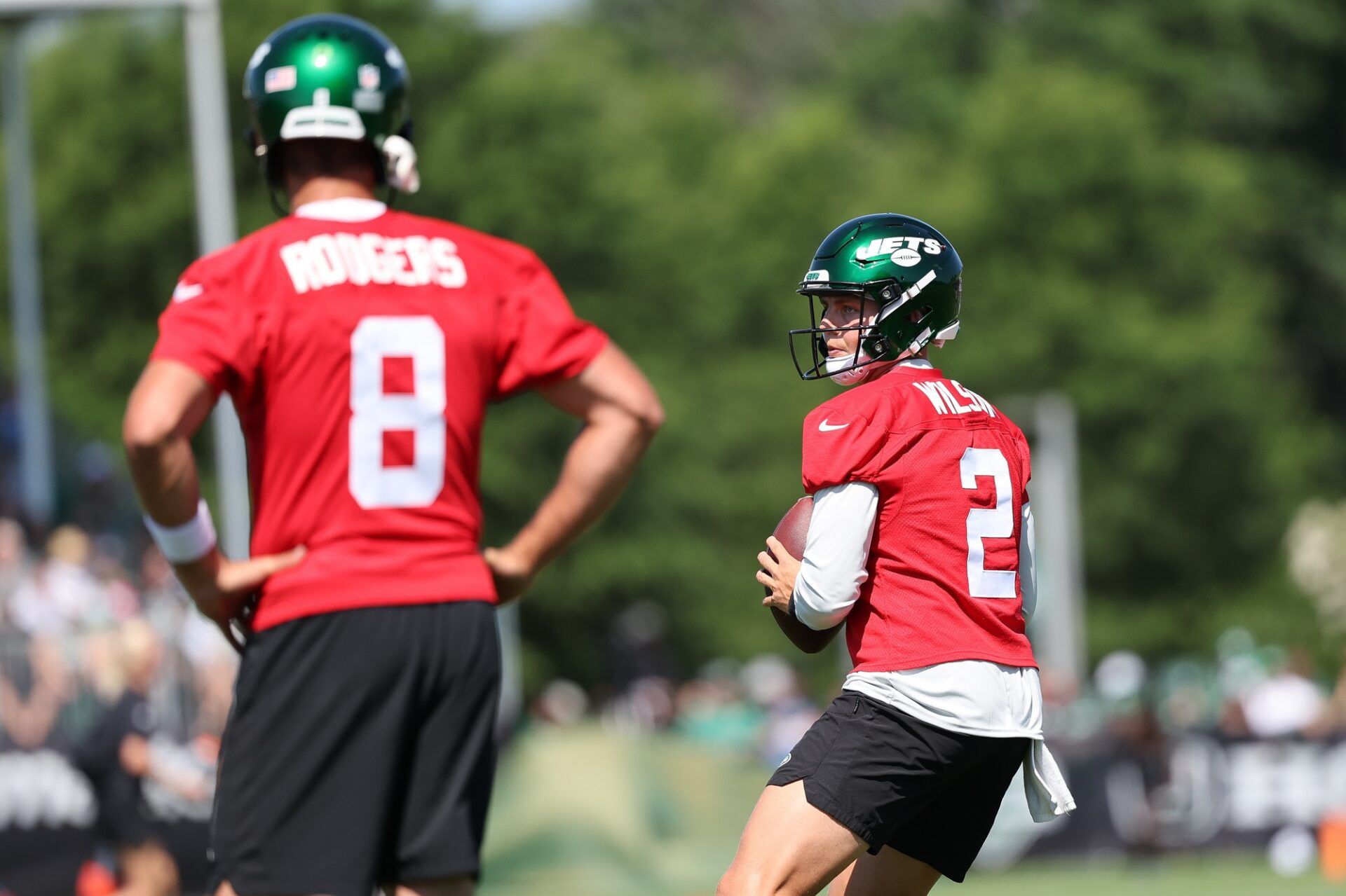 New York Jets QB Zach Wilson (2) throws passes during training camp while QB Aaron Rodgers (8) looks on.