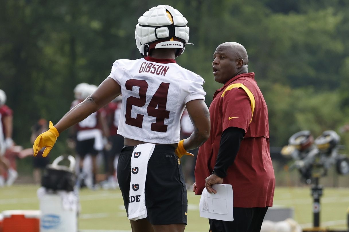 Washington Commanders offensive coordinator Eric Bieniemy talks with RB Antonio Gibson (24) during training camp.