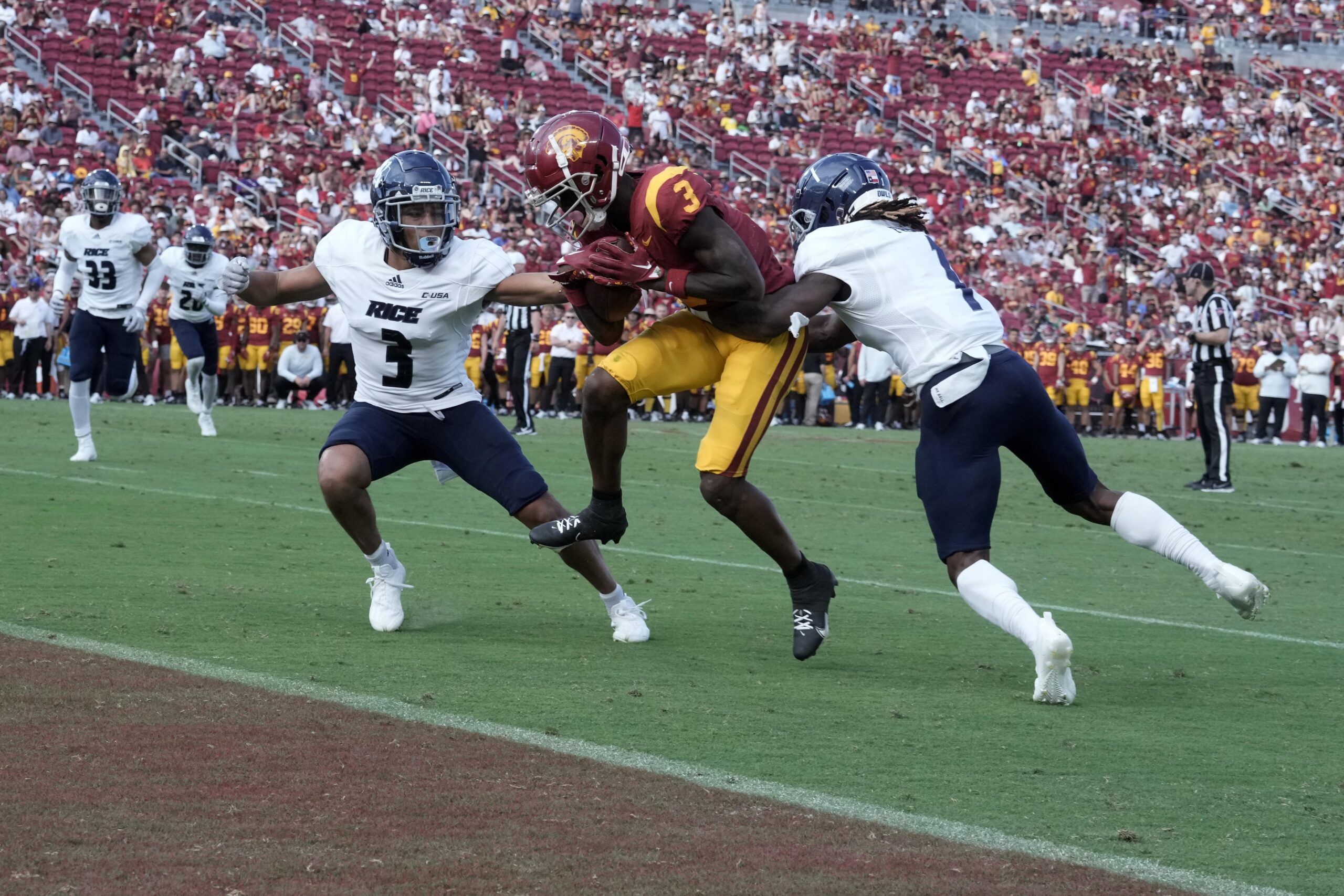 Jordan Addison (3) scores a touchdown in the second half as Rice Owls cornerback Jordan Dunbar (3) and cornerback Sean Fresch (1) defend at United Airlines Field at Los Angeles Memorial Coliseum.