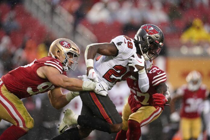 Tampa Bay Buccaneers RB Rachaad White (29) tries to break away from San Francisco 49ers DE Nick Bosa (97).