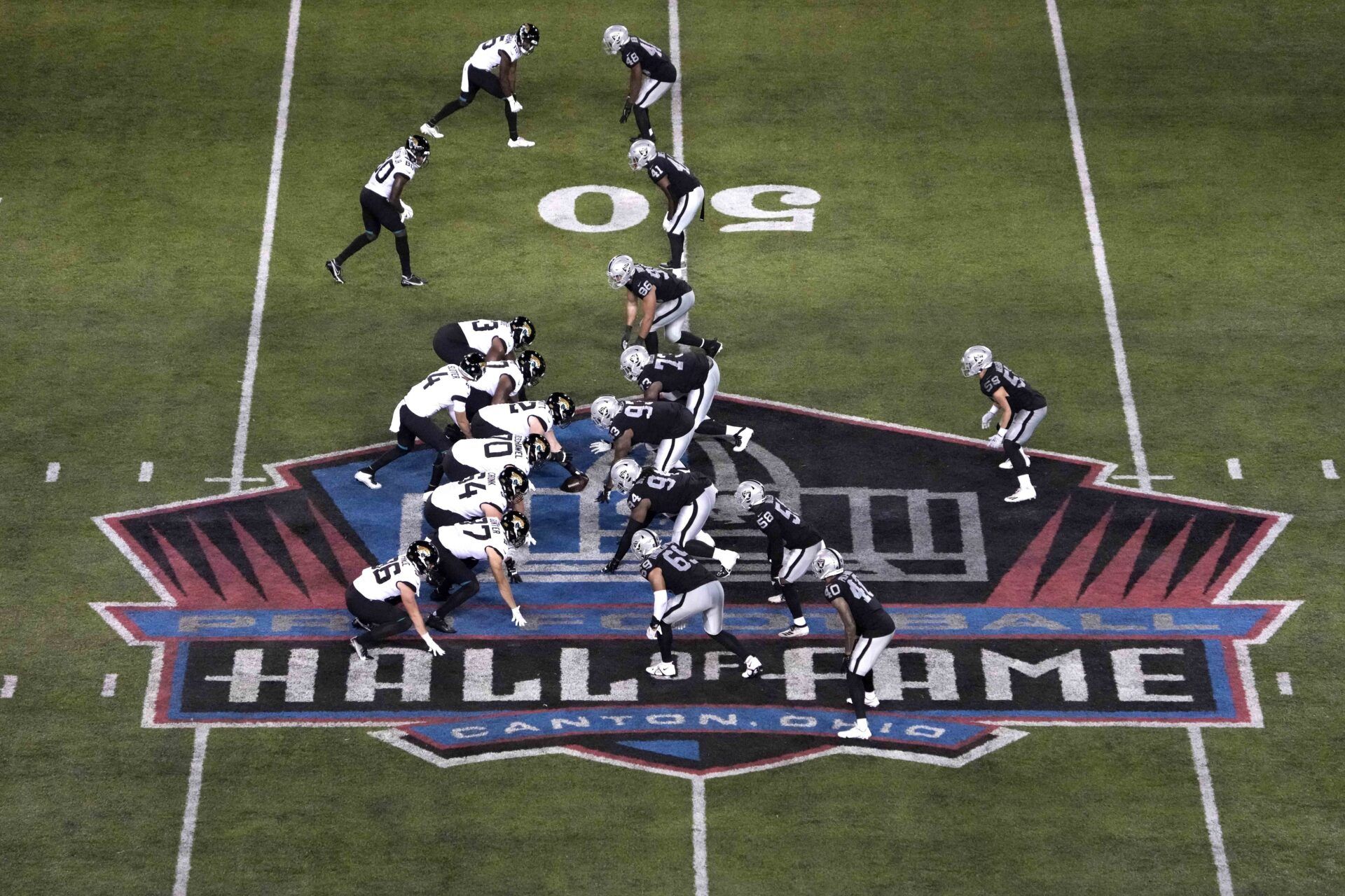 A general overall view as Jacksonville Jaguars quarterback Kyle Sloter (4) prepares to take the snap from offensive tackle KC McDermott (62) against the Las Vegas Raiders on the Pro Football Hall of Fame logo at midfield at Tom Benson Hall of Fame Stadium.