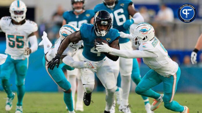 Jacksonville Jaguars running back Tank Bigsby (4) rushes for yards against Miami Dolphins safety Jevon Holland (8) and cornerback Noah Igbinoghene (9) during the second quarter of a preseason matchup Saturday, Aug. 26, 2023 at EverBank Stadium in Jacksonville, Fla. The game was suspended in the fourth after Miami Dolphins wide receiver Daewood Davis (87) was injured on a play with the Jaguars leading 31-18.