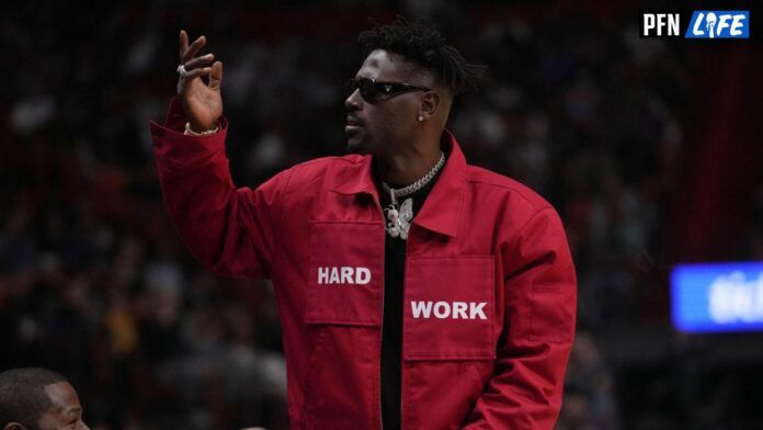 Former NFL player Antonio Brown gestures to the fans while standing in from t of former professional boxer Floyd Mayweather Jr. during the second half between the Miami Heat and the Brooklyn Nets at FTX Arena.