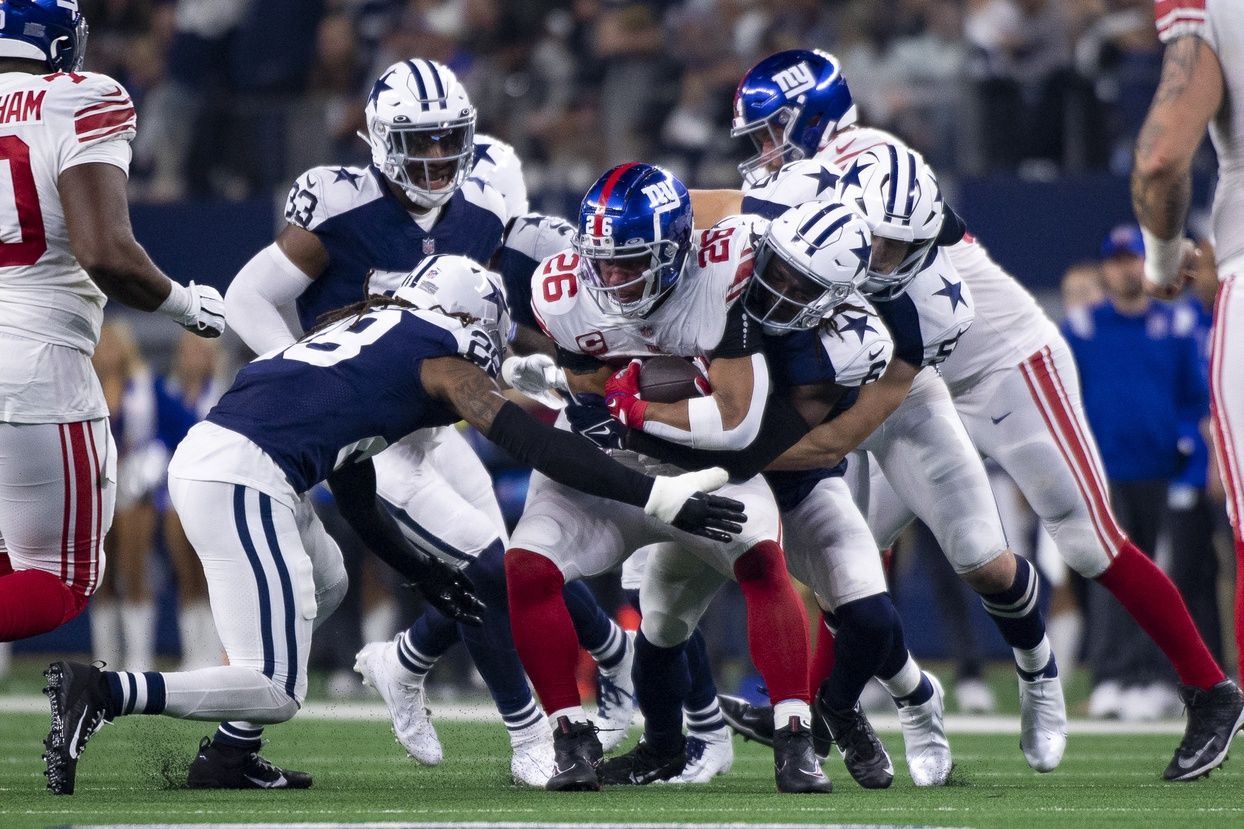 New York Giants running back Saquon Barkley (26) is tackled by the Dallas Cowboys defense during the second half of the game between the Cowboys and the Giants at AT&T Stadium.