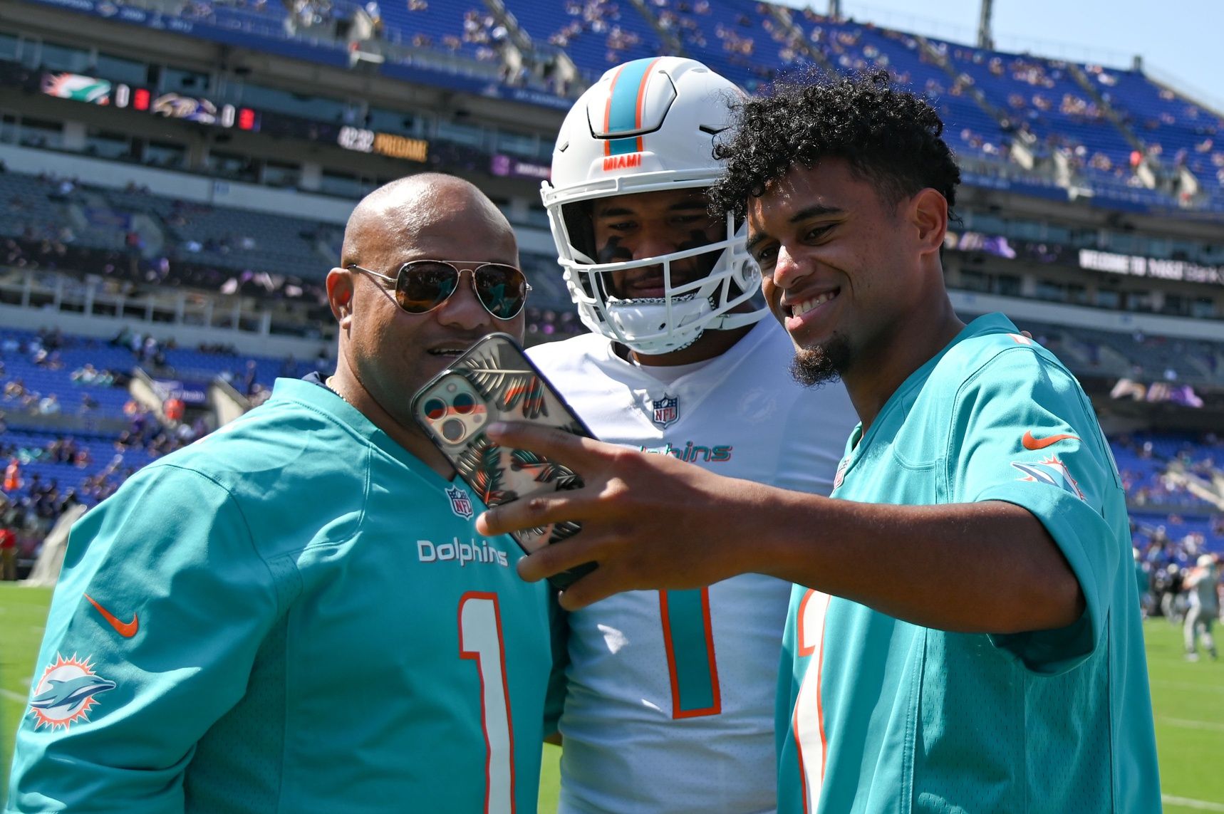 Taulia Tagovailoa takes a selfie with Miami Dolphins quarterback Tua Tagovailoa (1) and their father Galu on the sidelines before the game against the Baltimore Ravens at M&T Bank Stadium.