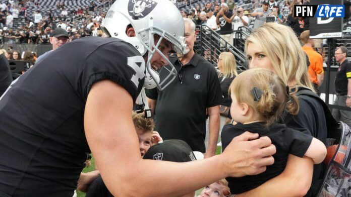 Quarterback Derek Carr shares a moment with his wife and daughter on the field.