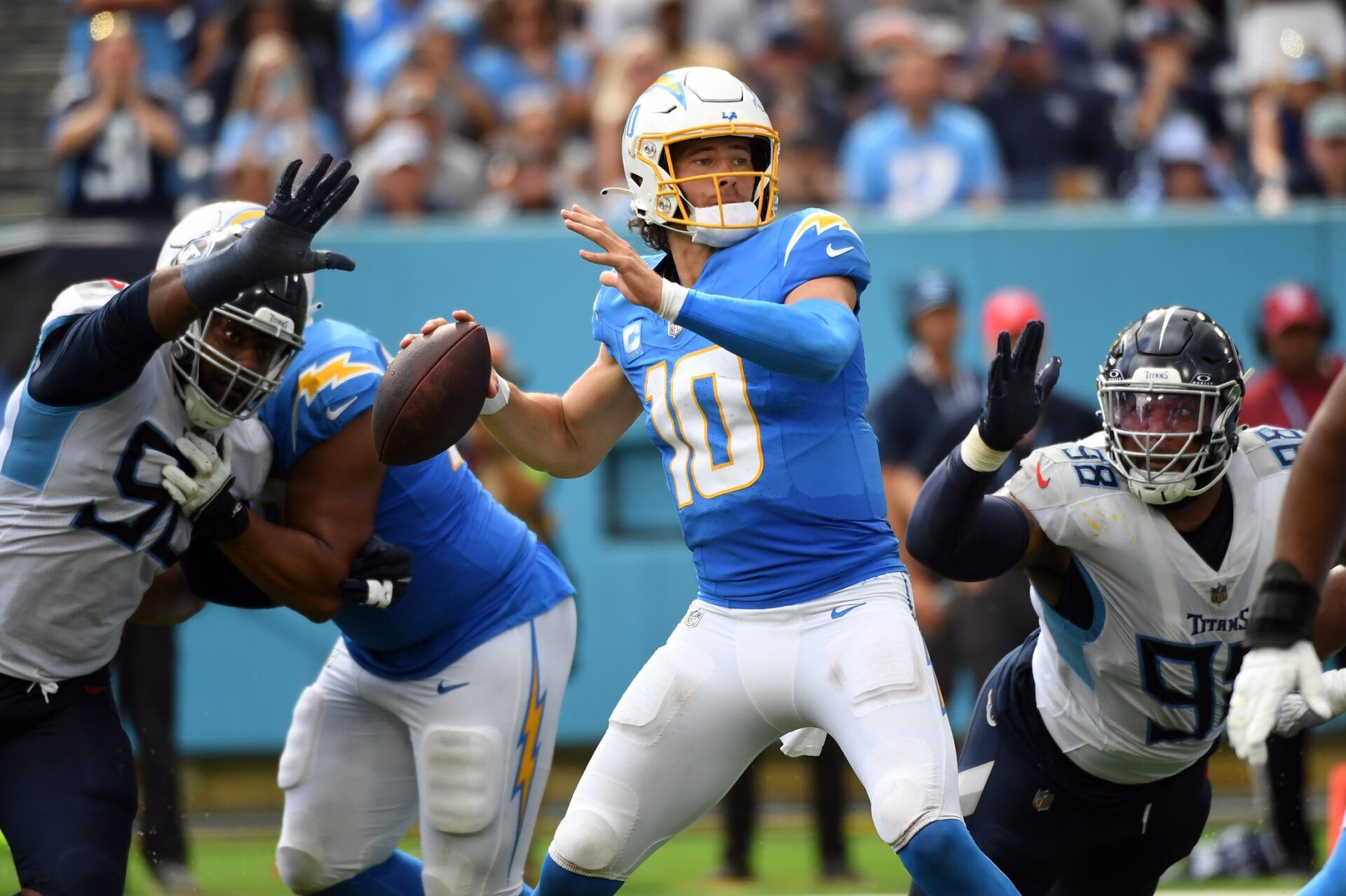 Justin Herbert (10) attempts a pass as he is pressured by Tennessee Titans defensive end Denico Autry (96) and defensive tackle Jeffery Simmons (98) in overtime at Nissan Stadium.