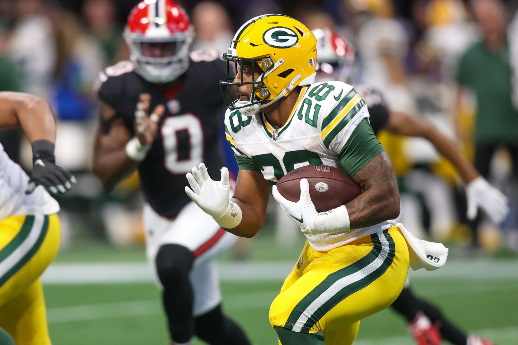 AJ Dillon (28) runs the ball against the Atlanta Falcons in the first quarter at Mercedes-Benz Stadium.