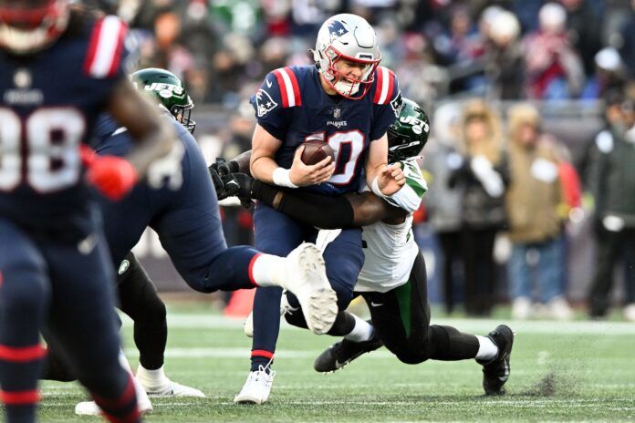 New England Patriots QB Mac Jones (10) gets sacked by New York Jets DE Micheal Clemons (72).