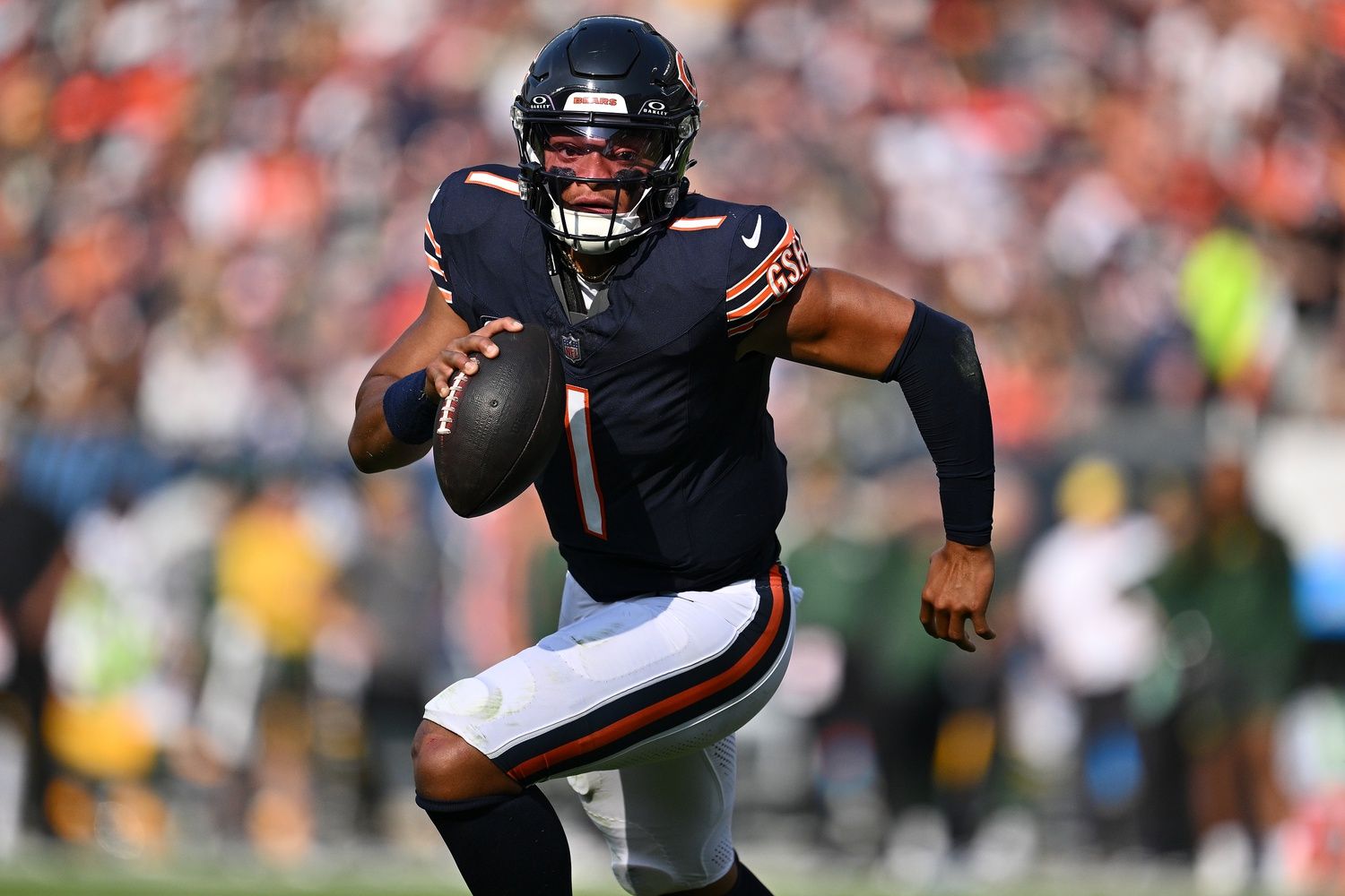 Justin Fields (1) runs the ball in the first half against the Green Bay Packers at Soldier Field.