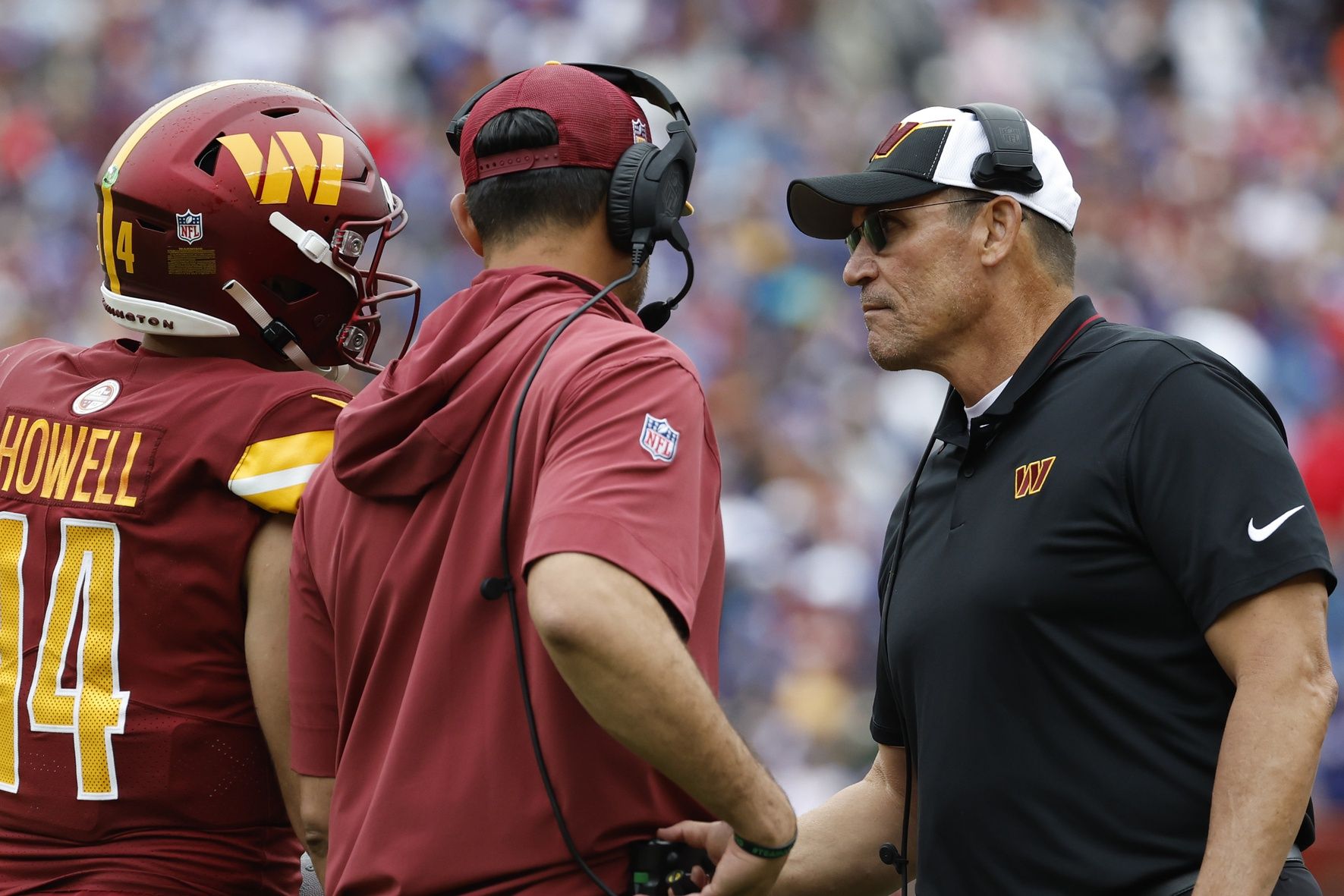 Ron Rivera (R) shakes hands with Commanders quarterback Sam Howell (14) after an interception against the Buffalo Bills during the third quarter at FedExField.