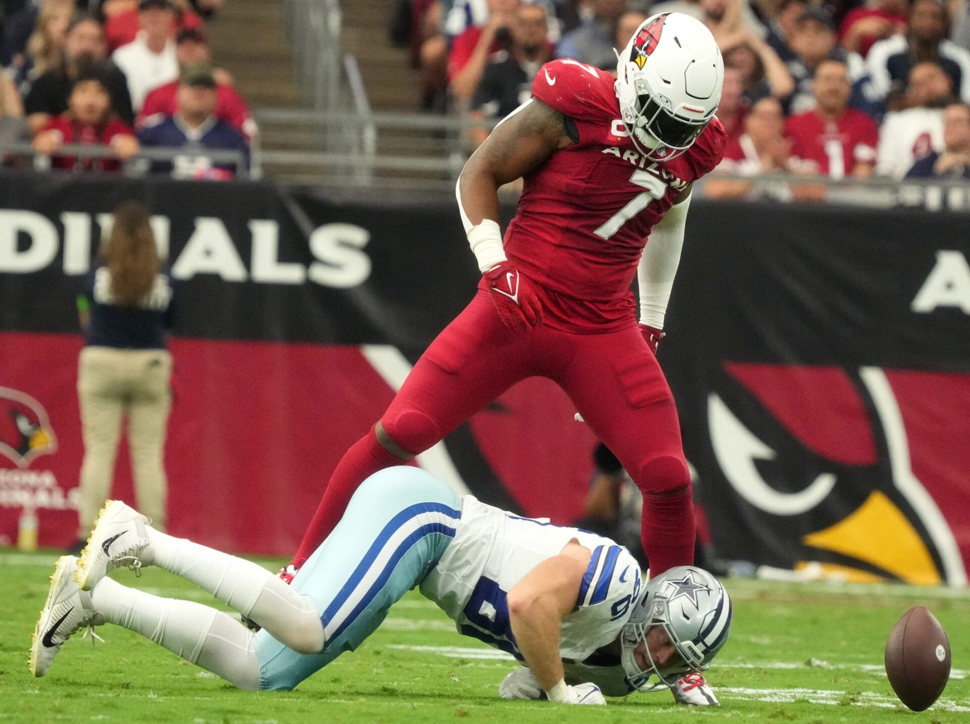 Kyzir White (7) stands over Dallas Cowboys tight end Luke Schoonmaker (86) after breaking up a pass play at State Farm Stadium.