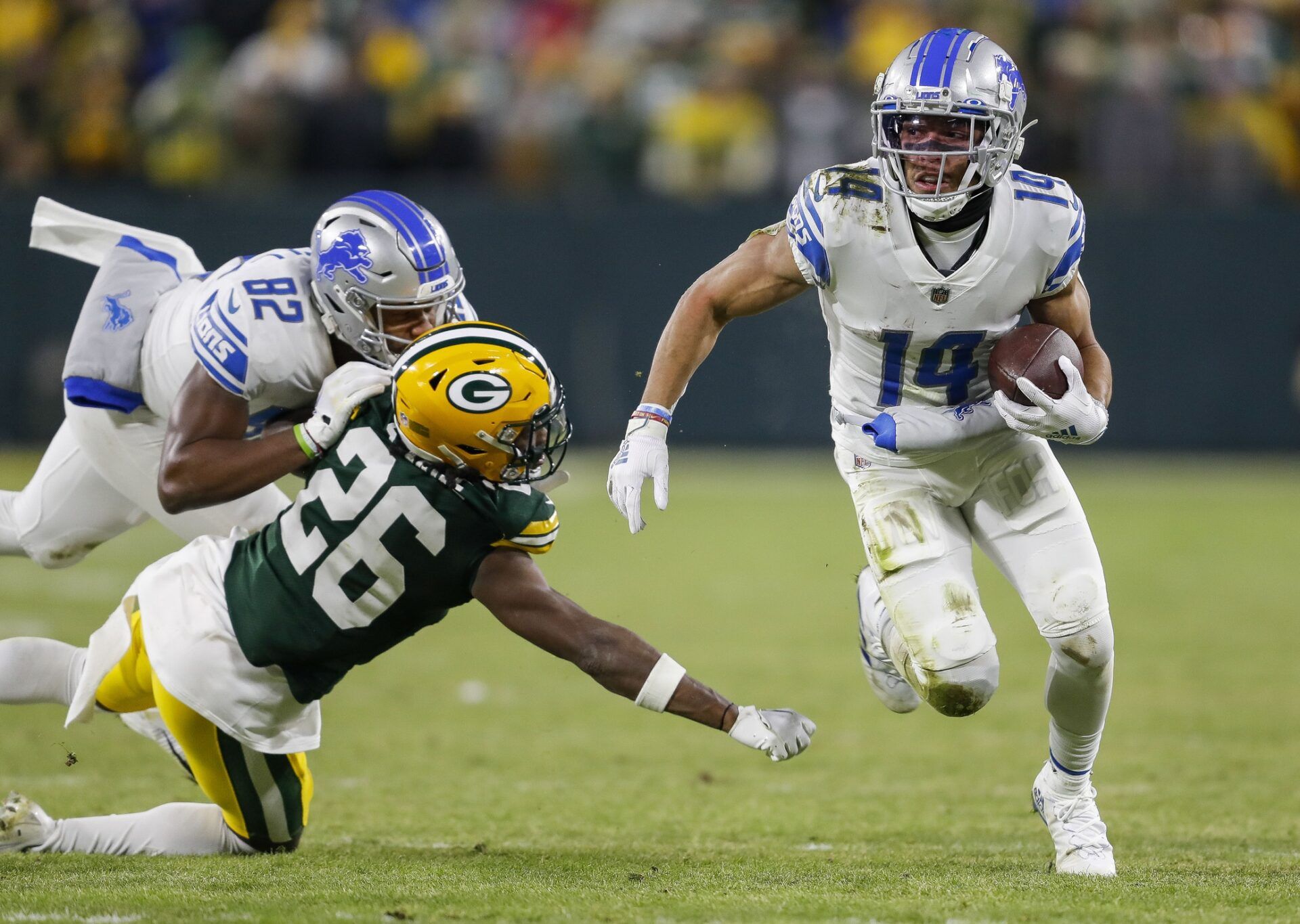 Amon-Ra St. Brown (14) runs the ball after making a reception against the Green Bay Packers at Lambeau Field.