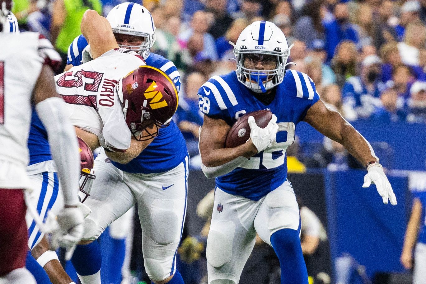 Jonathan Taylor (28) runs the ball while Washington Commanders linebacker David Mayo (51) defends in the second quarter at Lucas Oil Stadium.