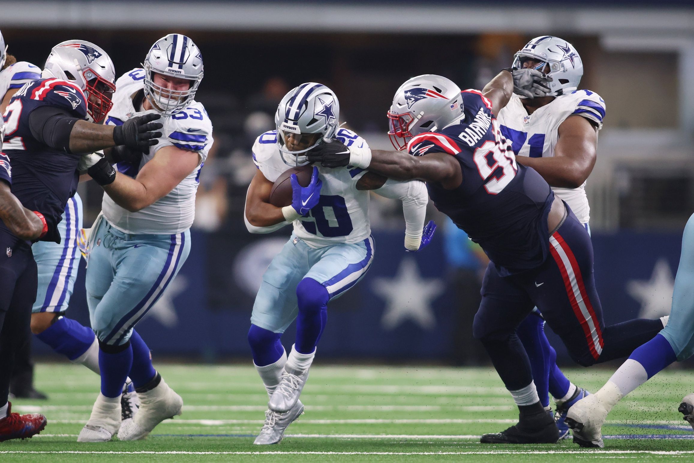 Tony Pollard (20) has his face mask grabbed by New England Patriots defensive tackle Christian Barmore (90) in the third quarter at AT&T Stadium.