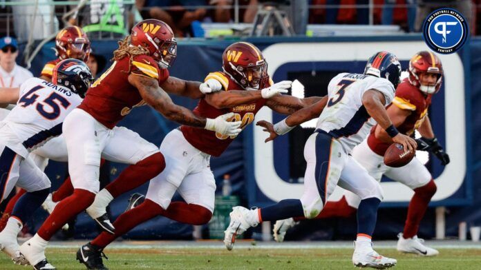 Denver Broncos quarterback Russell Wilson (3) scrambles under pressure from Washington Commanders defensive end Montez Sweat (90) and defensive end Chase Young (99) in the fourth quarter at Empower Field at Mile High.