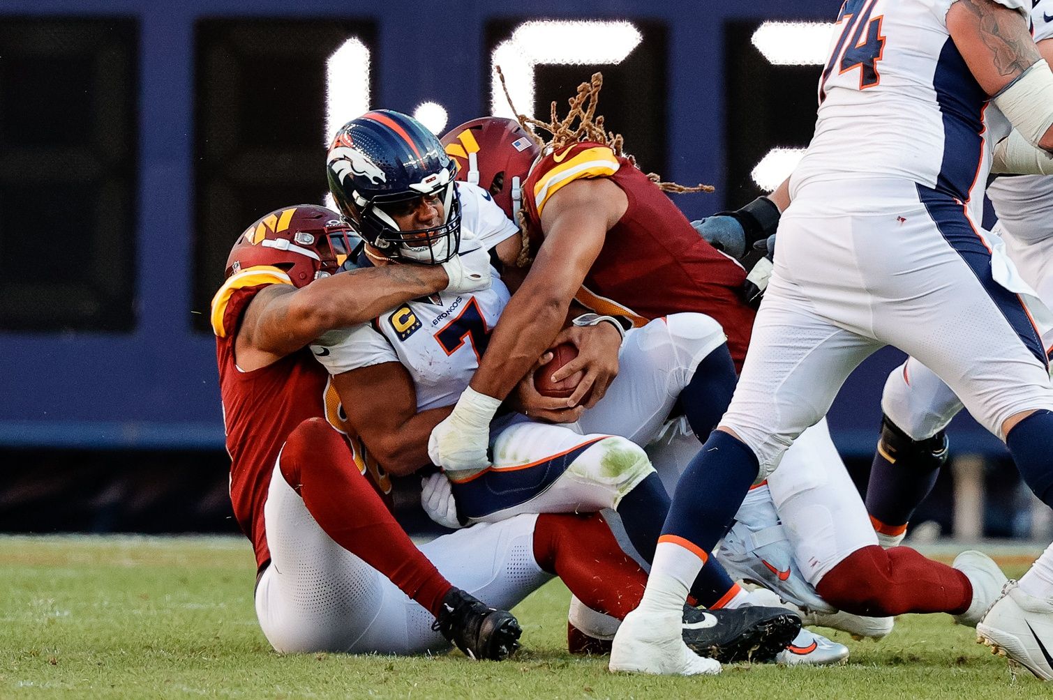 Russell Wilson (3) is sacked by Washington Commanders defensive end Montez Sweat (90) and defensive end Chase Young (99) in the fourth quarter at Empower Field at Mile High.