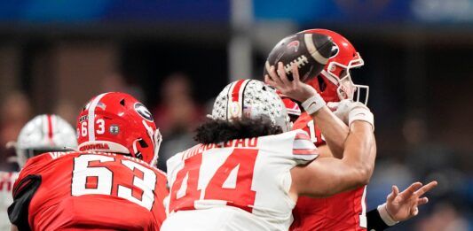 Ohio State Buckeyes defensive end J.T. Tuimoloau (44) hits the arm of Georgia Bulldogs quarterback Stetson Bennett (13) as the throws the ball in the third quarter during the Peach Bowl in the College Football Playoff semifinal at Mercedes-Benz Stadium.